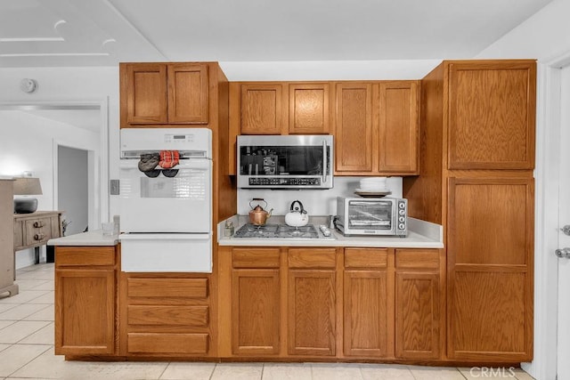 kitchen with a toaster, a warming drawer, stainless steel appliances, and light countertops