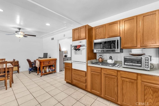 kitchen featuring appliances with stainless steel finishes, a toaster, light tile patterned floors, light countertops, and a warming drawer