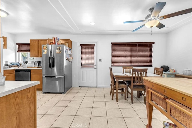 kitchen featuring ceiling fan, light countertops, brown cabinetry, freestanding refrigerator, and dishwashing machine