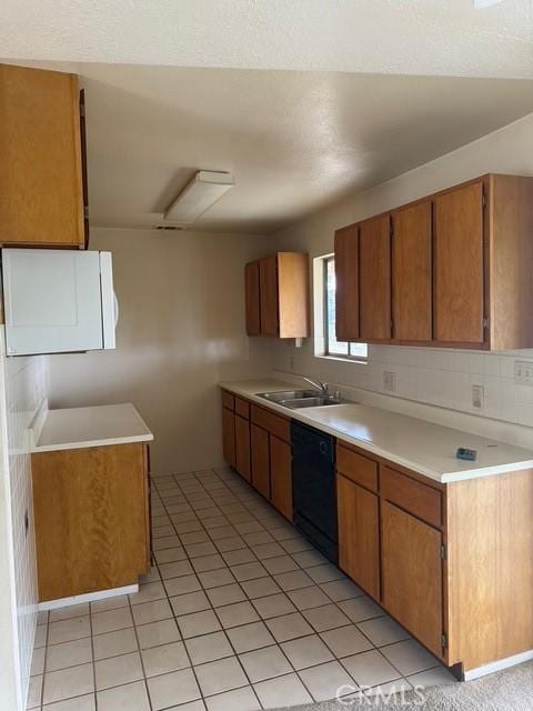 kitchen featuring brown cabinets, dishwasher, a sink, light countertops, and light tile patterned flooring
