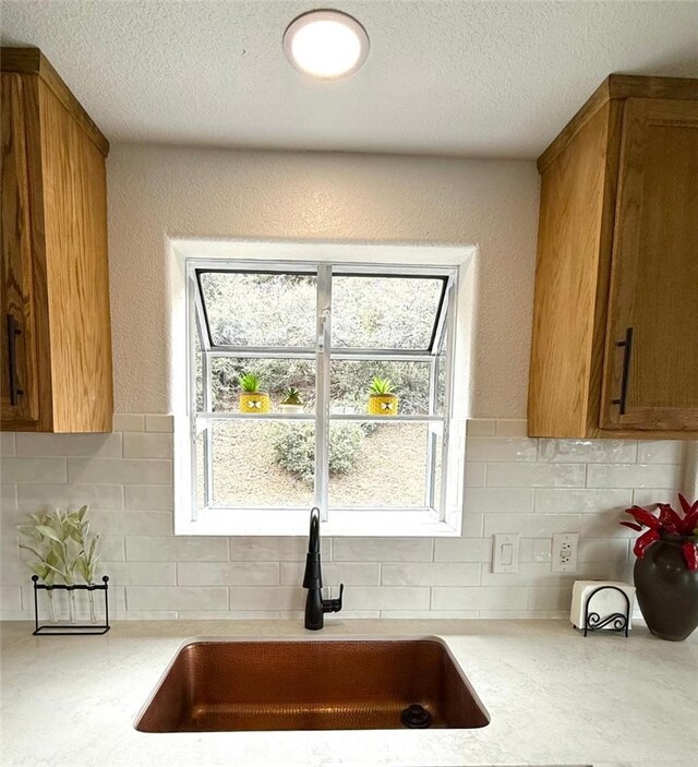 1909 Pioneer Way, Pine Mountain Club, CA 93222 - kitchen featuring light countertops, brown cabinetry, decorative backsplash, a textured ceiling, and healthy amount of natural light