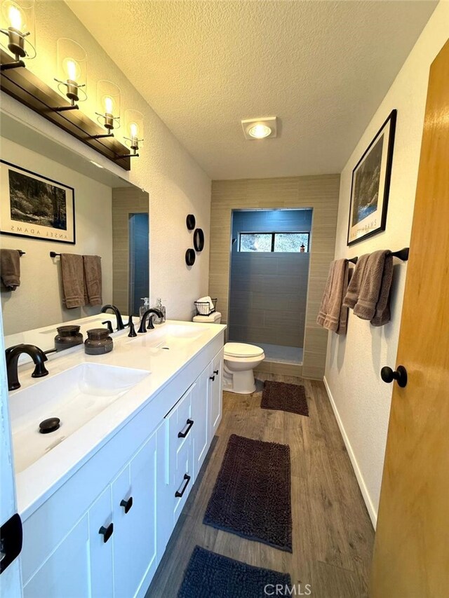 1909 Pioneer Way, Pine Mountain Club, CA 93222 - bathroom with a textured ceiling, double vanity, a tile shower, and wood finished floors