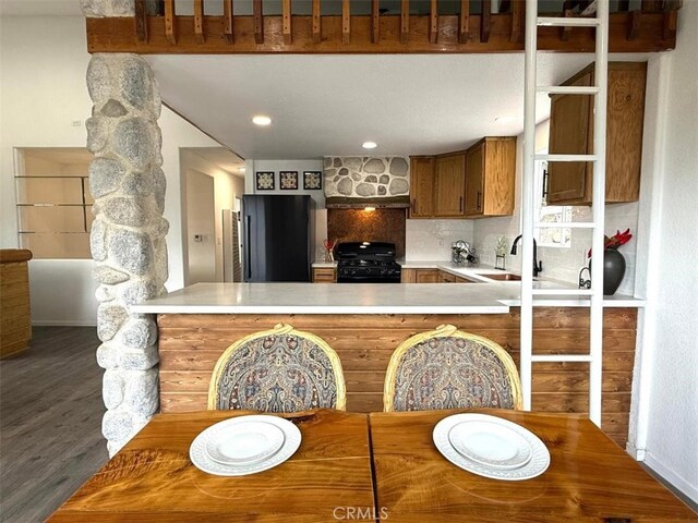 1909 Pioneer Way, Pine Mountain Club, CA 93222 - kitchen featuring fridge, black gas range oven, a peninsula, light countertops, and wood finished floors