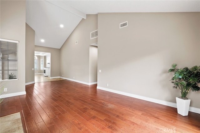 spare room featuring beam ceiling, wood finished floors, and visible vents