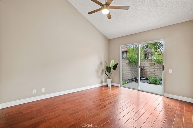 empty room with wood finished floors, baseboards, a textured ceiling, a ceiling fan, and vaulted ceiling