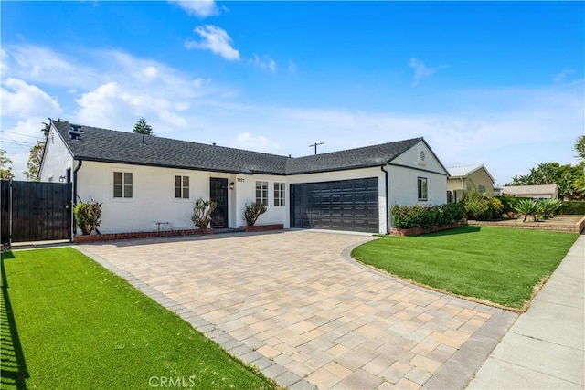 single story home featuring decorative driveway, fence, a front lawn, an attached garage, and stucco siding