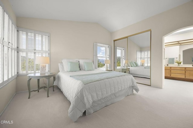 bedroom featuring arched walkways, light carpet, lofted ceiling, and a closet