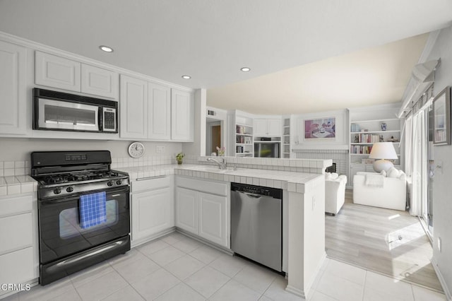 kitchen featuring tile countertops, appliances with stainless steel finishes, a peninsula, and open floor plan