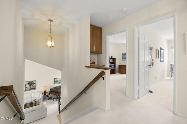 hall with baseboards, an upstairs landing, and light colored carpet