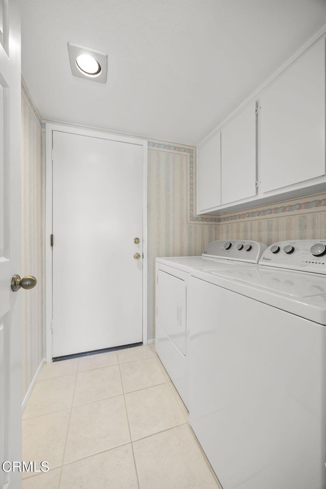 laundry area featuring light tile patterned floors, wallpapered walls, cabinet space, and washing machine and clothes dryer