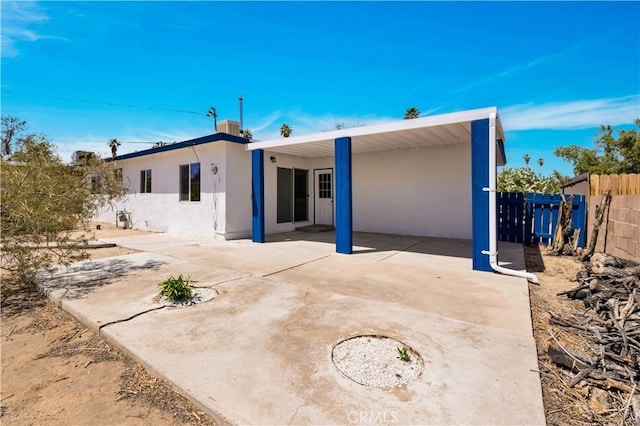 rear view of property featuring a patio, central AC, fence, and stucco siding