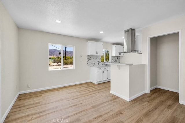 kitchen featuring light countertops, light wood-style floors, white cabinetry, and island range hood