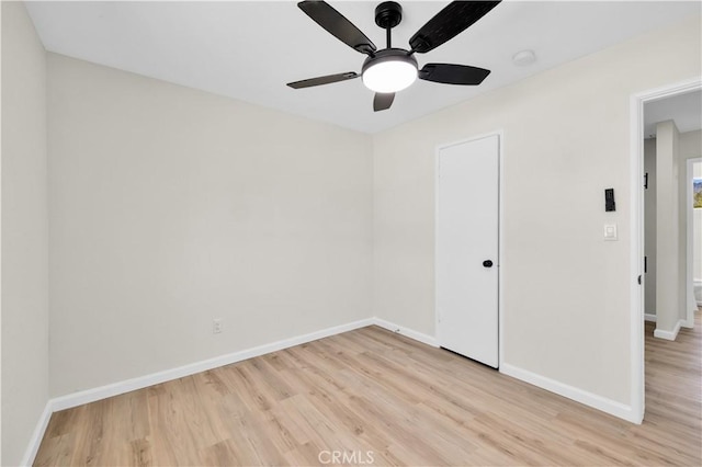 empty room featuring a ceiling fan, baseboards, and light wood finished floors