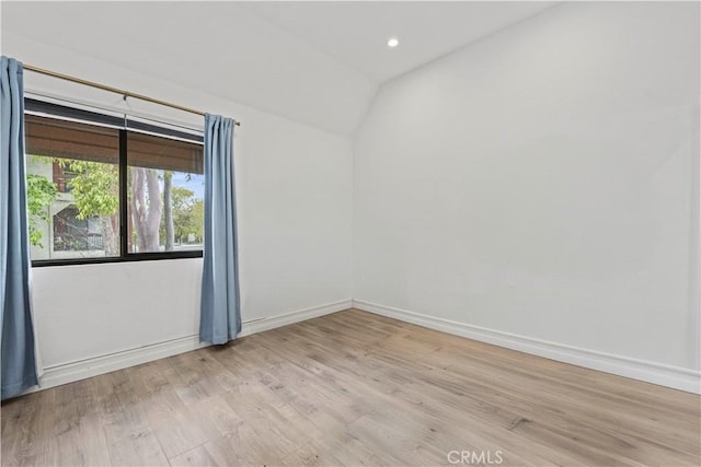 empty room with baseboards, vaulted ceiling, recessed lighting, and light wood-style flooring