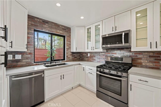 kitchen with white cabinets, appliances with stainless steel finishes, a sink, light countertops, and light tile patterned floors