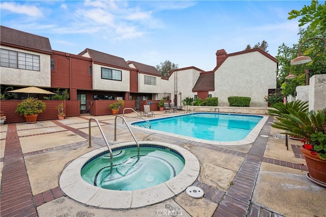 community pool featuring fence, a community hot tub, a patio area, and a residential view