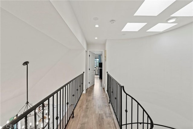 hall with recessed lighting, light wood finished floors, and a skylight