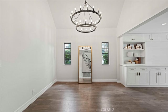 interior space featuring baseboards, dark wood-style flooring, a notable chandelier, and high vaulted ceiling