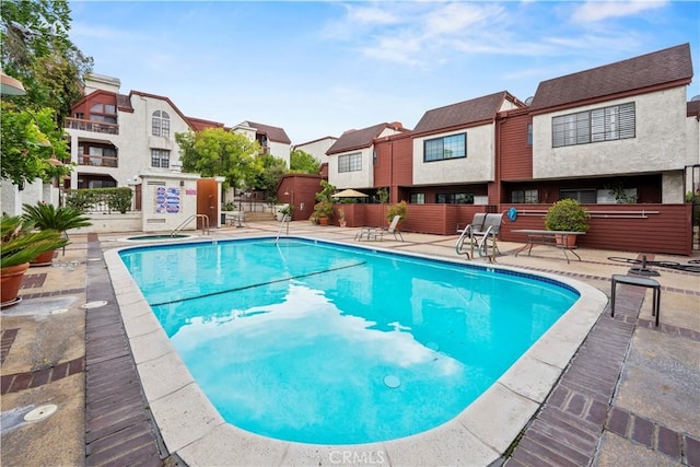 community pool with fence, a residential view, and a patio area
