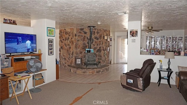 living room with carpet flooring, a ceiling fan, a textured ceiling, and a wood stove