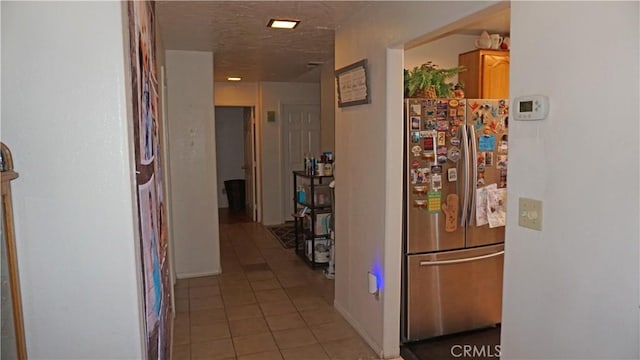 hall featuring baseboards and light tile patterned flooring
