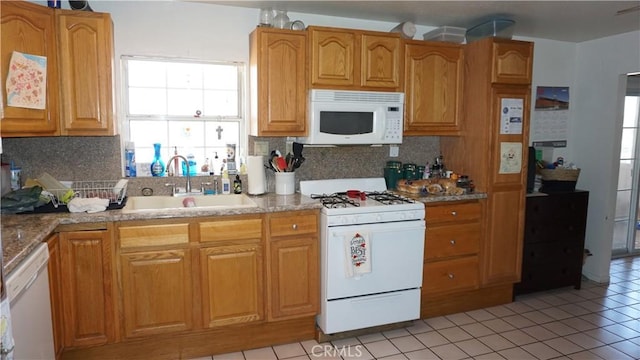 kitchen featuring a sink, light tile patterned floors, decorative backsplash, and white appliances