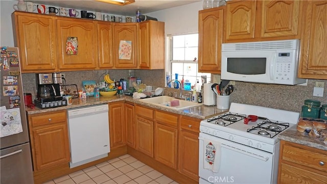 kitchen with a sink, light tile patterned floors, white appliances, and tasteful backsplash