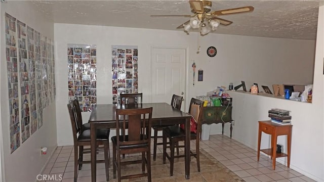 tiled dining room with a textured ceiling and ceiling fan