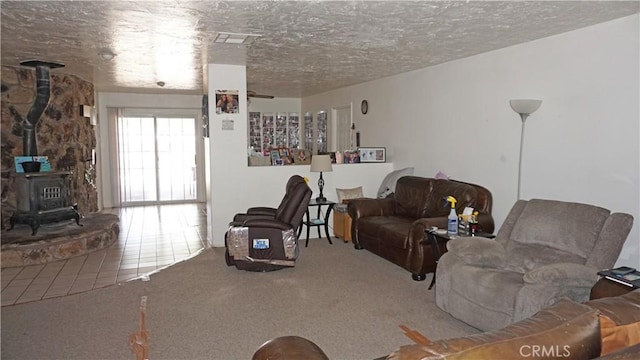 living area featuring a wood stove, carpet flooring, and a textured ceiling