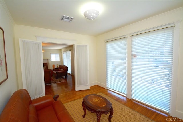 living area featuring baseboards, visible vents, and wood finished floors