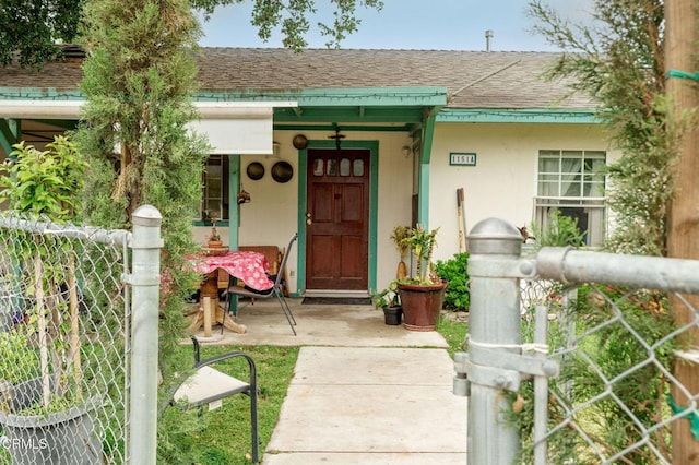 doorway to property with fence, a shingled roof, and stucco siding