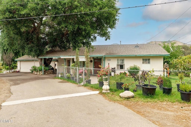 ranch-style house featuring a detached garage, covered porch, a fenced front yard, and stucco siding