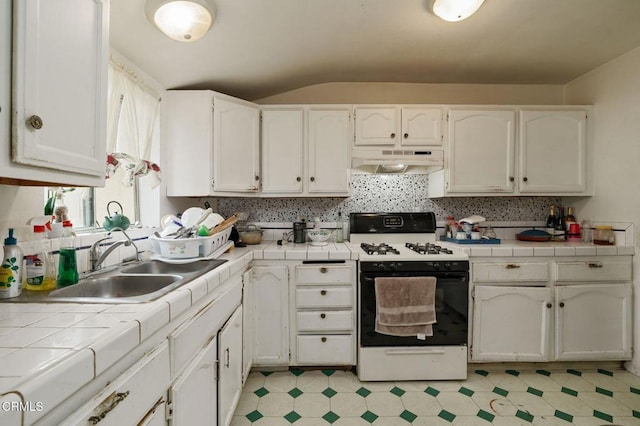 kitchen featuring under cabinet range hood, tile counters, a sink, and gas range