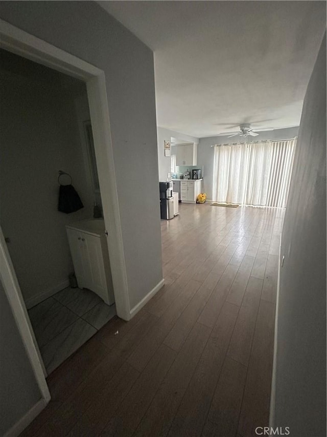 hallway featuring baseboards and dark wood-style floors