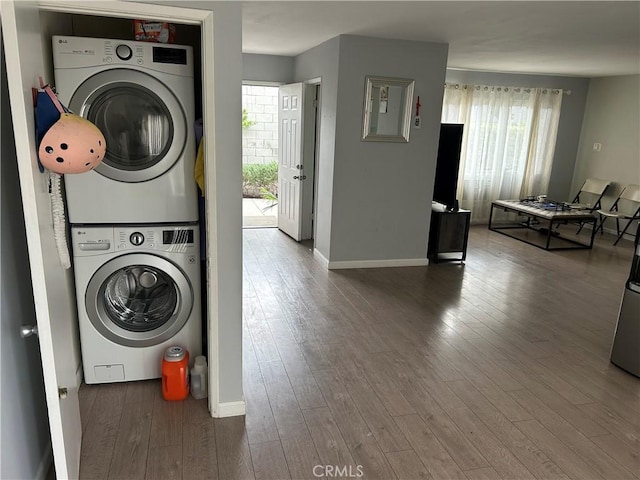 washroom featuring laundry area, a healthy amount of sunlight, stacked washer and clothes dryer, and wood finished floors