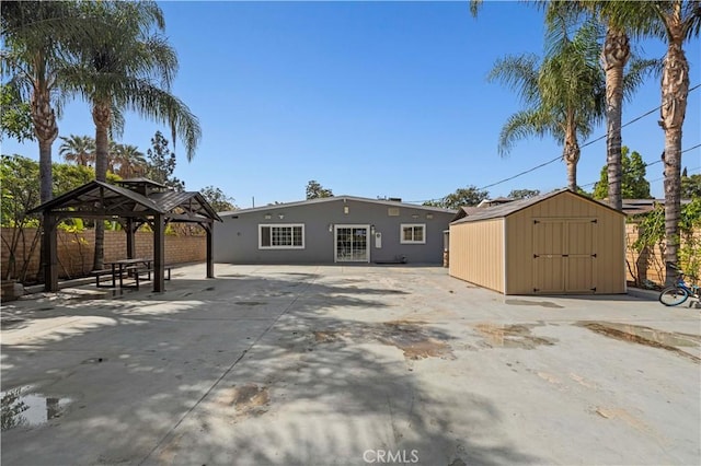 back of property with a gazebo, fence, an outdoor structure, a shed, and stucco siding