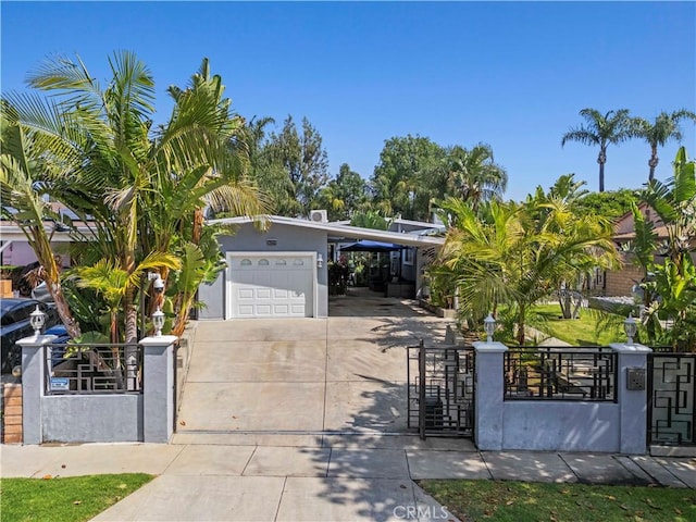 view of front facade featuring a fenced front yard, stucco siding, a gate, concrete driveway, and an attached carport