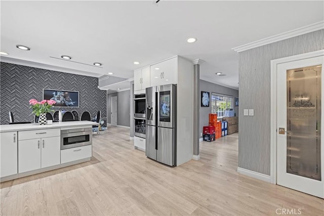 kitchen featuring stainless steel appliances, wallpapered walls, ornamental molding, and an accent wall