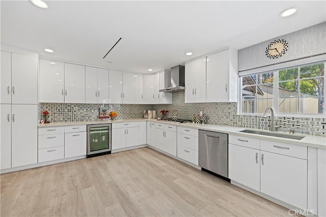 kitchen with wall chimney range hood, a sink, dishwasher, beverage cooler, and tasteful backsplash