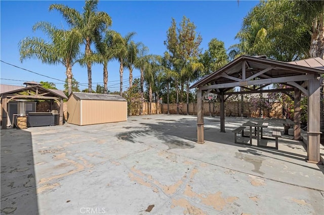view of patio / terrace with fence, a storage unit, a jacuzzi, a gazebo, and an outbuilding