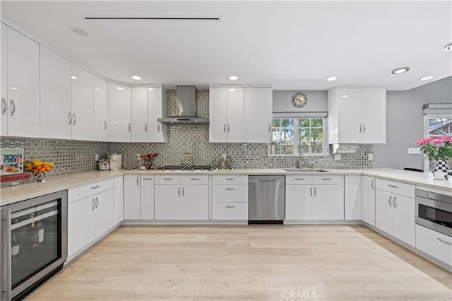 kitchen featuring wine cooler, modern cabinets, wall chimney exhaust hood, a sink, and appliances with stainless steel finishes