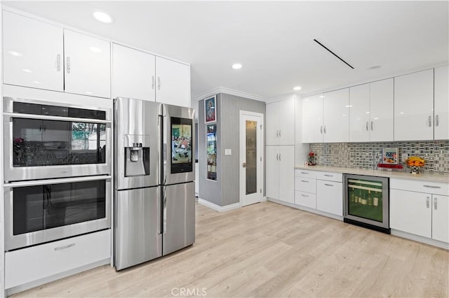kitchen featuring stainless steel appliances, light wood-type flooring, beverage cooler, and white cabinetry