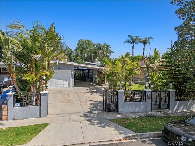 view of front of property with driveway, a fenced front yard, a gate, a carport, and stucco siding