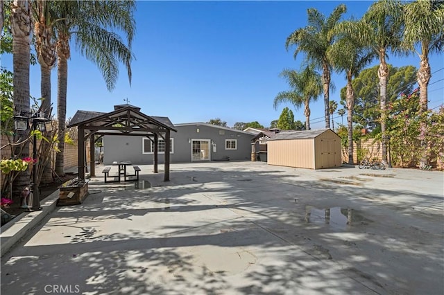 back of house with an outdoor structure, a gazebo, stucco siding, and a shed