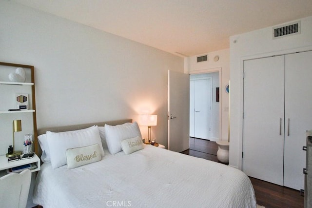 bedroom featuring a closet, dark wood finished floors, and visible vents