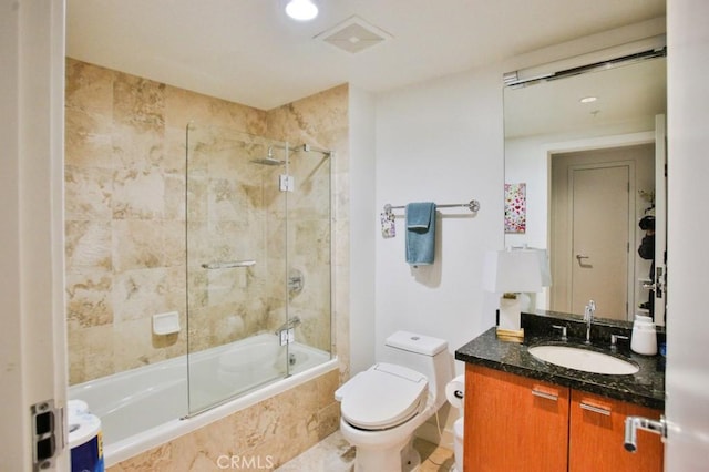 full bathroom featuring vanity, tiled shower / bath, and toilet