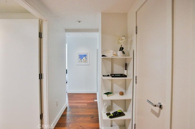 hallway featuring baseboards and wood finished floors