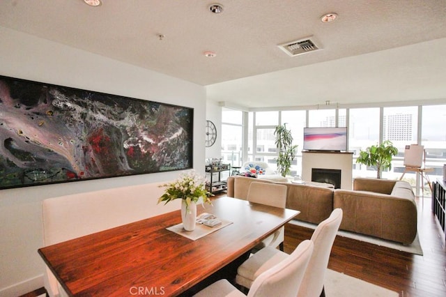 dining area with plenty of natural light, wood finished floors, visible vents, and a fireplace
