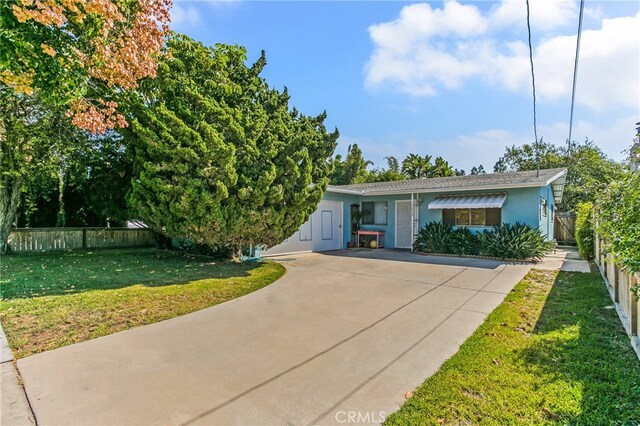 view of front facade with fence, driveway, a front yard, and stucco siding