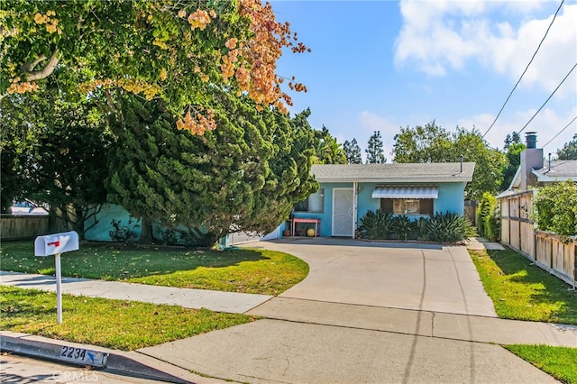 view of front facade with fence, stucco siding, concrete driveway, and a front lawn